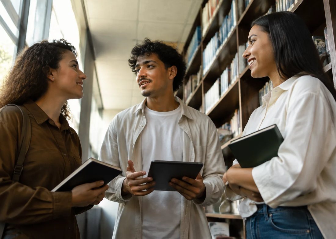 Participantes conversando de pé entre estantes altas de livros
